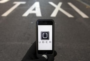 The logo of car-sharing service app Uber on a smartphone over a reserved lane for taxis in a street is seen in this photo illustration taken in Madrid on December 10, 2014. REUTERS/Sergio Perez