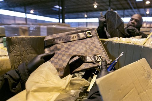 In this Wednesday, Oct. 28, 2015, photo, counterfeit Louis Vuitton bags are found in a shipment by U.S. Customs and Border Protection officers, including Gabriel Richardson, right, at H&M Terminals Transport Inc. warehouse, in Kearney, N.J. Counterfeiting is a multibillion-dollar business in China, which produces nearly nine of every 10 fake items seized at U.S. borders. (AP Photo/Richard Drew)