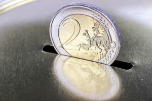 Two-euro coin inserting it into a piggy bank as savings