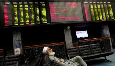 A man takes a nap on a couch under an electronic board displaying share prices during trading session at the Karachi Stock Exchange April 2, 2014. REUTERS/Akhtar Soomro/File Photo