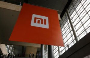 People stand near a logo of Xiaomi ahead of the launching ceremony of Xiaomi Phone 4, in Beijing, July 22, 2014. Picture taken July 22, 2014. REUTERS/Jason Lee