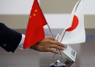 A staff member of Japan's minister of economy, trade and industry, arranges Chinese and Japanese flags before a meeting between a group of Chinese business leaders led by Gao Xiqing, president of China Investment Corp., and Toshimitsu Motegi, minister at the ministry, both unseen, in Tokyo, Japan, on Thursday, Sept. 26, 2013. A group of heads of ten Chinese companies are on a five-day trip to Japan. Photographer: Tomohiro Ohsumi/Bloomberg via Getty Images