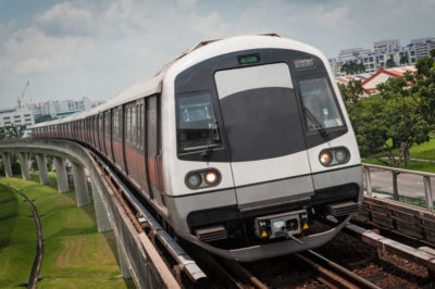 Modern metro train speeding through city suburbs on elevated railway, Singapore. ProPhoto RGB profile for maximum color fidelity and gamut.