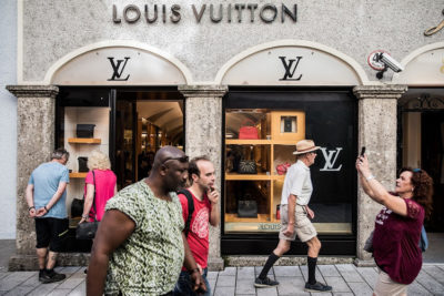 Pedestrians walk by a LVMH Moet Hennessy Louis Vuitton SE luxury store store on the Getreidegasse shopping precinct in Salzburg, Austria, on Wednesday, Sept. 12, 2018. Pumped-hydro plants like Kaprun, with 830 megawatts of capacity, can store enough power to cover almost 100,000 households for more than a week. Photographer: Akos Stiller/Bloomberg