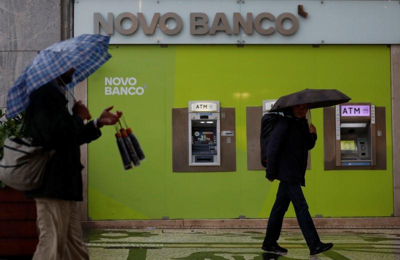 A man sells umbrellas near ATM machines of a Novo Banco branch in downtown Lisbon, Portugal April 10, 2018.  REUTERS/Rafael Marchante