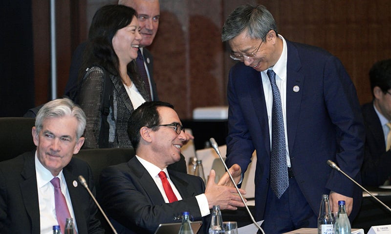 US Treasury Secretary Steven Mnuchin (C, seated) and China's Central Bank Governor Yi Gang (R) shake hands prior to the G20 finance ministers and central bank governors meeting in Fukuoka on June 8, 2019. (Photo by Eugene Hoshiko / POOL / AFP)
