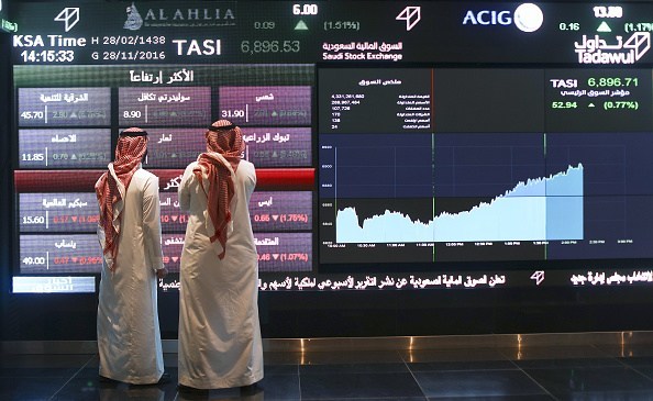 Visitors stand and watch stock movements displayed on large video screens inside the Saudi Stock Exchange, also known as the Tadawul All Share Index in Riyadh, Saudi Arabia, on Monday, Nov.28, 2016. The Tadawul All Share Index advanced 26 percent since Saudi Arabias record-breaking bond sale last month, the most in the world during that period. Photographer: Simon Dawson/Bloomberg via Getty Images