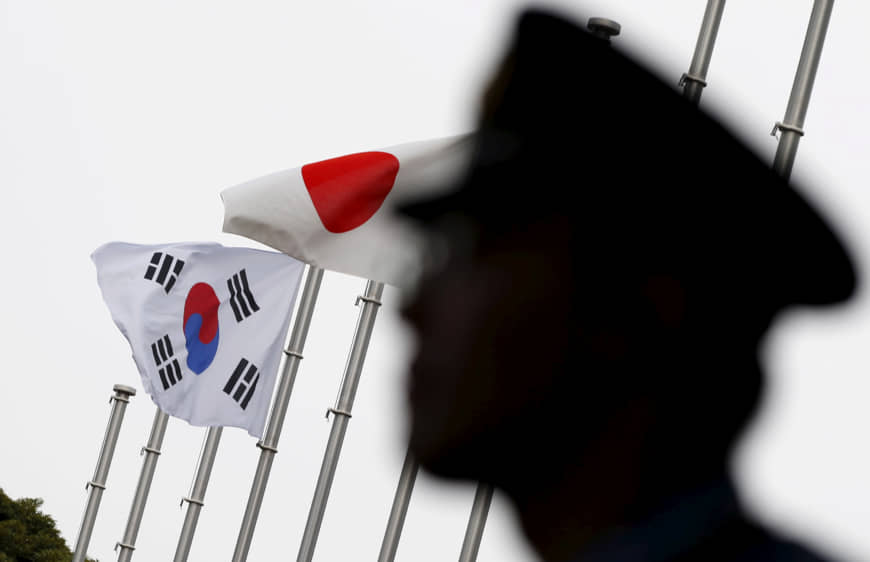 FILE PHOTO: A police officer stands guard near Japan and South Korea national flags at hotel, where South Korean embassy in Japan is holding the reception to mark the 50th anniversary of normalisation of ties between Seoul and Tokyo, in Tokyo June 22, 2015.  REUTERS/Toru Hanai/File Photo