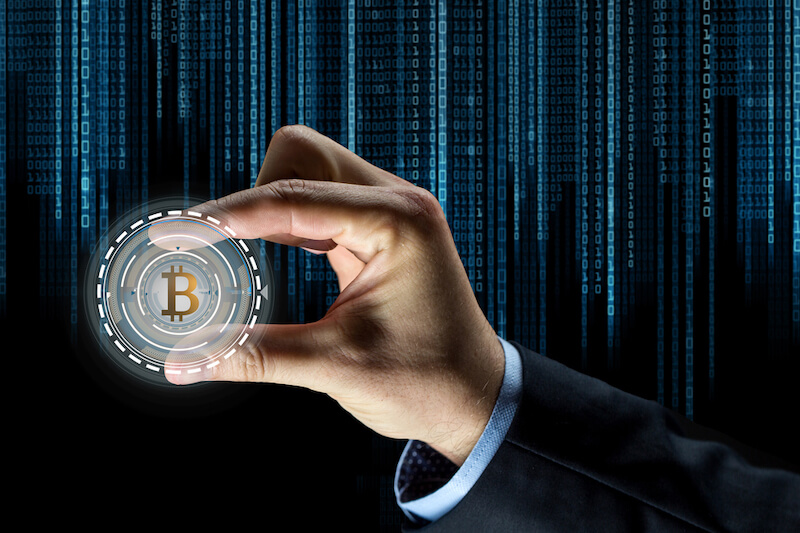 cryptocurrency, finance and business concept - close up of businessman hand with virtual bitcoin symbol hologram over binary code background
