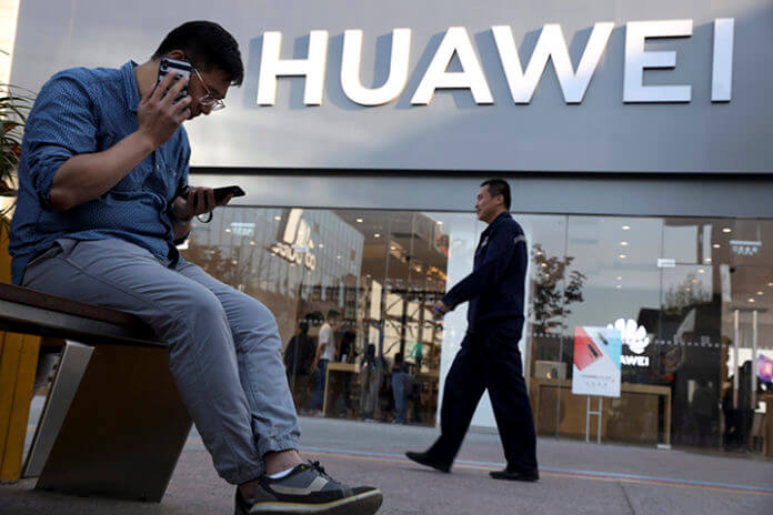 A man uses two smartphones at once outside a Huawei store in Beijing Monday, May 20, 2019. Google is assuring users of Huawei smartphones the American company's services still will work on them following U.S. government restrictions on doing business with the Chinese tech giant. (AP Photo/Ng Han Guan)