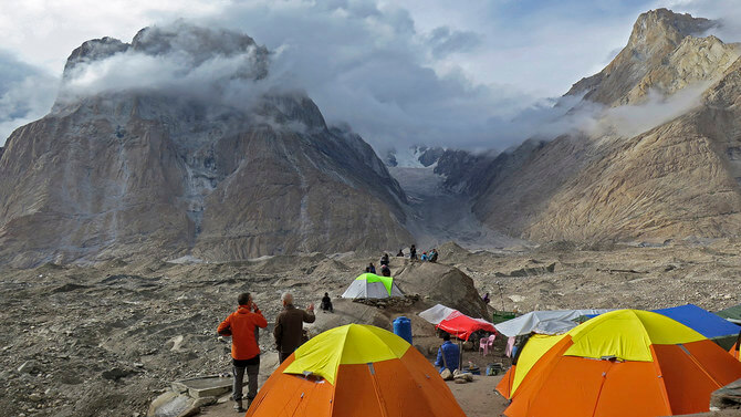 In this picture taken on August 12, 2019 foreign tourists and porters rest at a camping site above Baltoro glacier in the Karakoram range of Pakistan's mountain northern Gilgit region. - Northern Pakistan is home to some of the tallest mountains in the world, including K2, the world's second highest peak. Mountaineers have long been drawn to the area by the challenging climbs. (Photo by AMELIE HERENSTEIN / AFP)